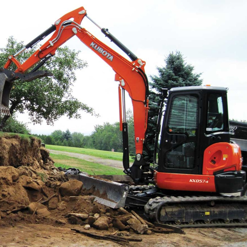 Orange Kubota KX057 excavator digging into a field. There are trees in the background 