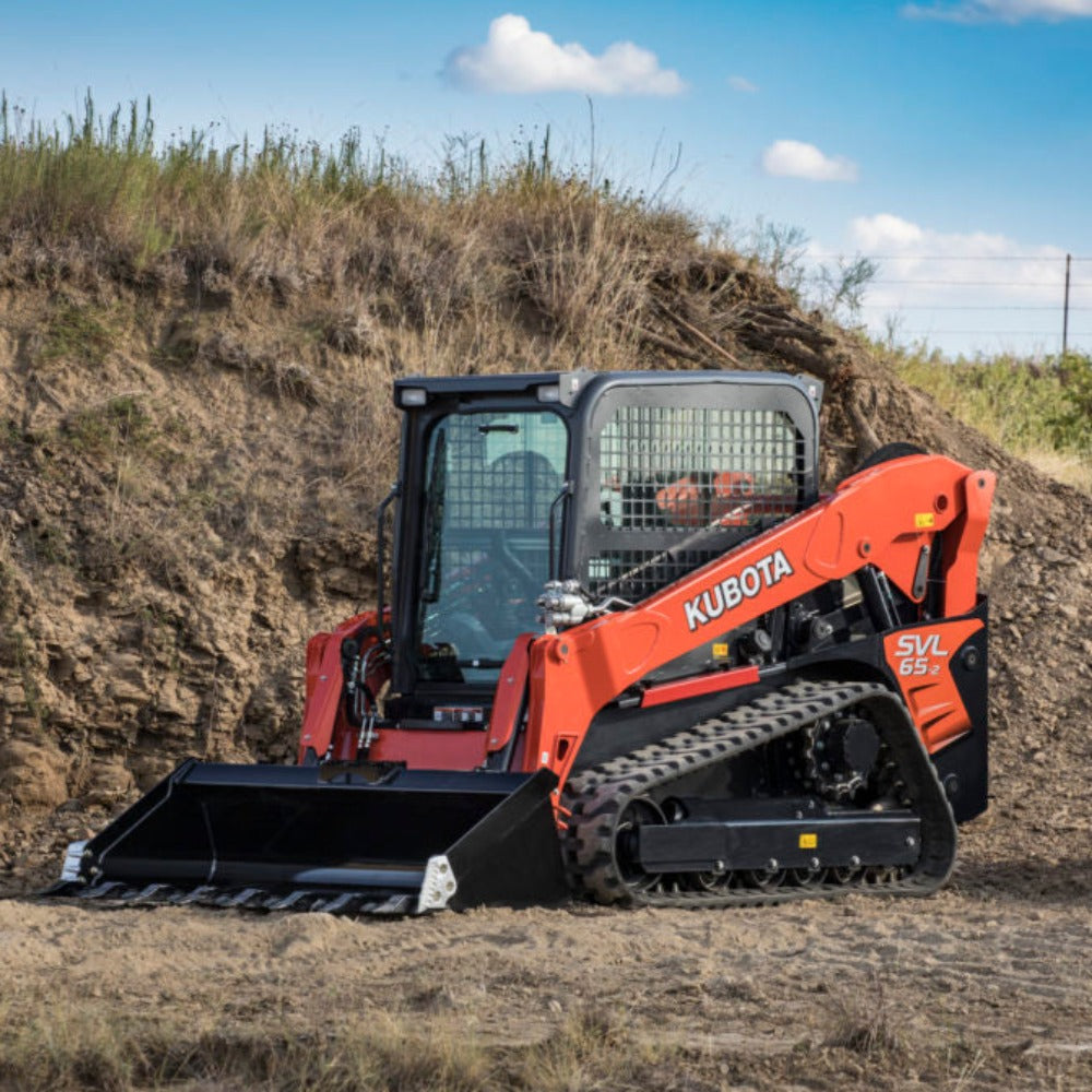 Orange Kubota SVL65 skid steer parked in front of a dirt pile